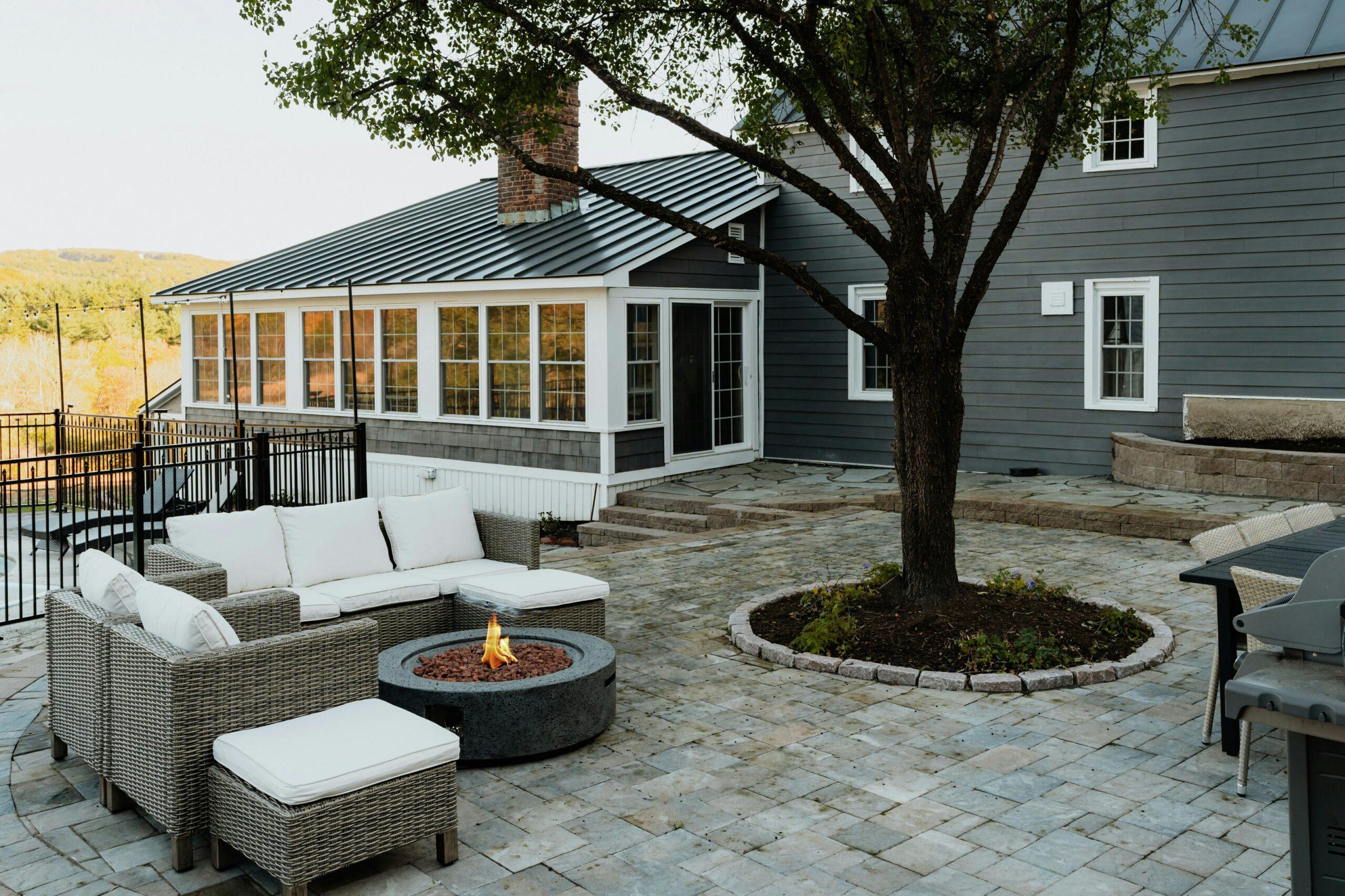 Photo of house with adirondack chairs around a firepit